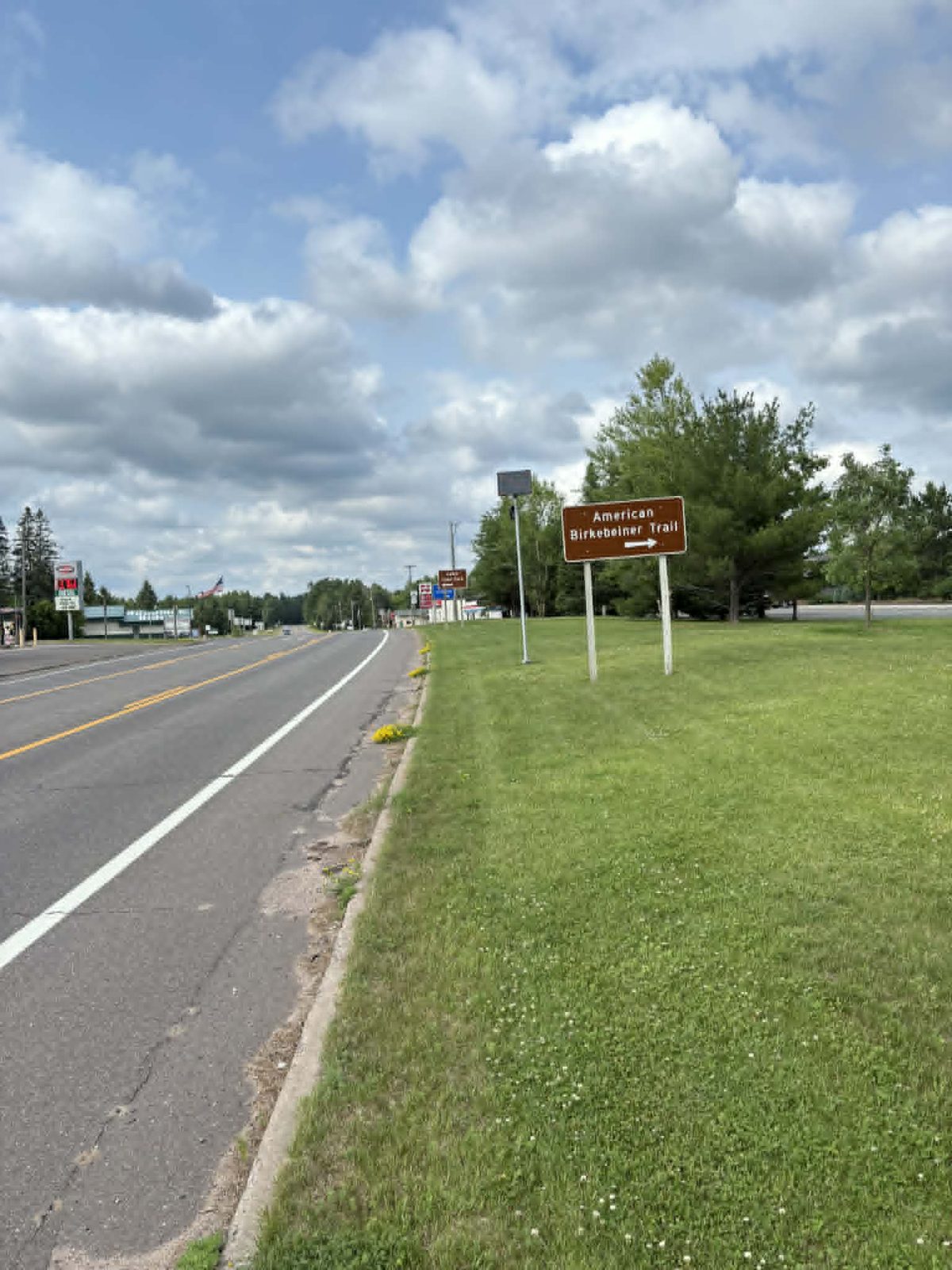 A solar-powered Flock license-plate camera on a pole beside US-63 in Cable, Wisconsin, near the American Birkebeiner Trail sign